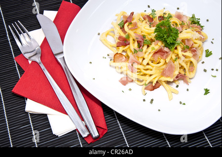 Portion frische Käse-Spätzle mit frischen Kräutern auf schwarze Tischdecke dekoriert Stockfoto