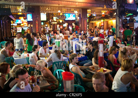 Ausländische Touristen und Backpacker trinken und Speisen Sie abends in eine Bar im Freien auf der Khao San Road, Bangkok, Thailand Stockfoto