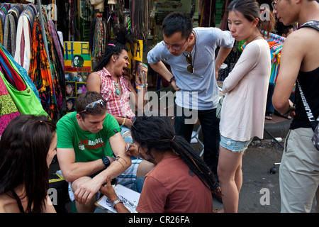 Ein ausländischer Tourist bekommt eine Tattoo auf der Khao San Road, Bangkok, Thailand. Stockfoto