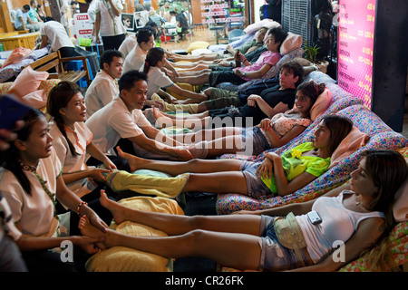 Ausländische Touristen erhalten Massage in der Öffentlichkeit auf der Khao San Road, Bangkok, Thailand. Stockfoto