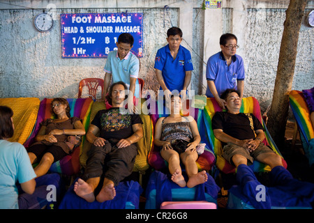 Ausländische Touristen erhalten Massage in der Öffentlichkeit auf Soi Rambuttri, Bangkok, Thailand. Stockfoto