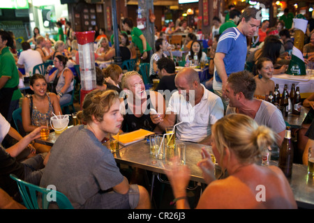 Ausländische Touristen und Backpacker trinken und Speisen Sie abends in eine Bar im Freien auf der Khao San Road, Bangkok, Thailand. Stockfoto