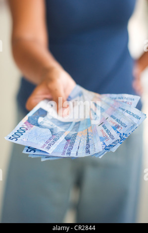 Nahaufnahme eines Stapels indonesische Rupiah, durch eine Frau ausgehändigt. Stockfoto