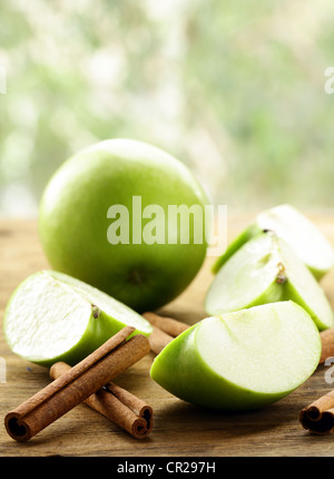 grüne Äpfel und Zimtstangen auf einem hölzernen Hintergrund Stockfoto