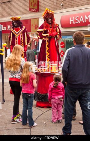 Stelzenläufer in "König und Königin der Herzen" Kostüme, Straßenkünstlern in Newton Abbot, Devon, UK. Stockfoto