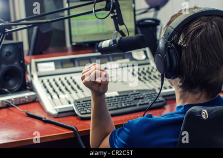 DJ vor ein Mikrofon im Radio von hinten arbeiten Stockfoto