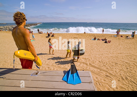 Eine braungebrannte Rettungsschwimmer wacht auf Strandbesucher, die den Sand und Pazifischen Ozean Surf in Newport Beach in Süd-Kalifornien, USA zu genießen. Stockfoto