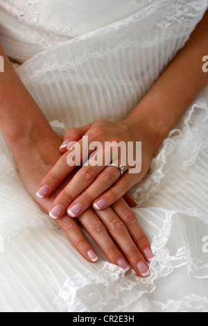 Hände der Braut auf einem Hintergrund von einem Brautkleid Stockfoto