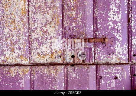 Hintergrund eines alten gemalt, zerbröckelte Tür. Griff auf lila Holzbohlen. Stockfoto