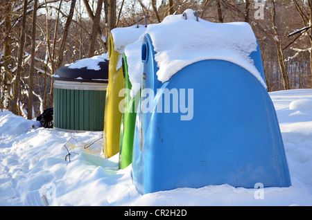 Mülltrennung-Container ist im Winter mit Schnee bedeckt. Papier, Glas und Kunststoff. Blaue, grüne und gelbe Farbe Behälter. Stockfoto