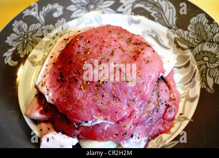 Geschnitten Sie Sliced Schweinekoteletts mit Tropf Gewürz zum Backen im Gericht zubereitet Steaks. Stockfoto