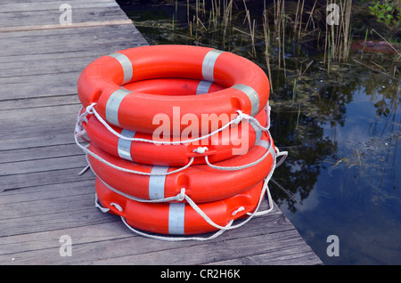 Rettungs-Kreise-Lebensretter Bojen orange gestapelt auf hölzernen See Brückenpfeilers. Stockfoto