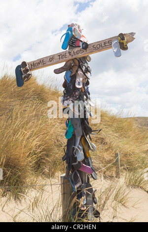Ein Mast mit vielen Sandalen und dem Text "Zuhause verloren Sohlen" Castlepoint, Wellington, New Zealand, Oceania Stockfoto