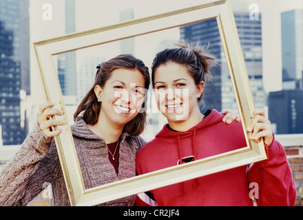 Zwei junge Frauen posieren mit Bilderrahmen, USA (Vintage 2003) Stockfoto