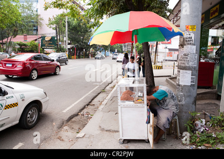 Einem schlafenden Straßenhändler, Erdnüsse zu verkaufen. Cebu City, Cebu, Visayas, Philippinen. Stockfoto