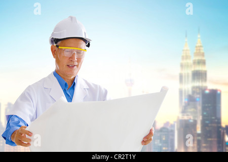 Asiatische Senior Ingenieur mit Blaupausen stehen außen modernes Gebäude Stockfoto