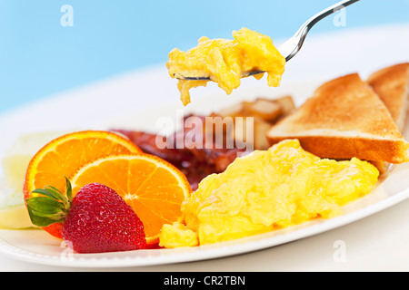 Rührei auf einer Gabel oben Frühstücksteller Obst Toast mit Speck Stockfoto