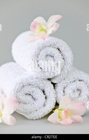 White Spa Handtücher mit Orchideen Blumen aufgerollt Stockfoto