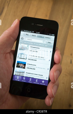 Ein iPhone 4G Smartphone verwenden, um ein Haus zu kaufen auf Zoopla Grundstück finden Anwendung finden Stockfoto