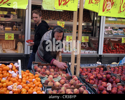 Frau Wahl Pfirsiche auf einem Obst- und Gemüsemarkt auf Rue Cler in Paris, Frankreich, 13. Mai 2012, © Katharine Andriotis Stockfoto