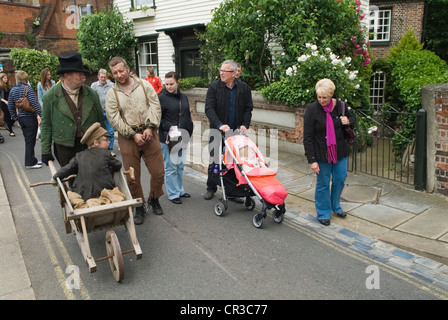 Die Dramatikgesellschaft feiert den britischen Autor Charles Dickens. Das jährliche Charles Dickens Festival. Ein Tourist schiebt den Kinderwagen mit, während der kleine Tim, eine Figur aus Einem Weihnachtslied, in einer Schubkarre durch die Straße geschoben wird. Rochester Kent England 2012 2010er Jahre Großbritannien. HOMER SYKES Stockfoto