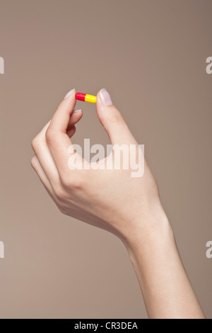 Hand einer jungen Frau hält eine Tablette, Kapsel zwischen ihren Fingern Stockfoto