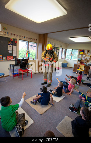 Feuerwehrmann im Gespräch mit Kindern im Vorschulalter. Stockfoto