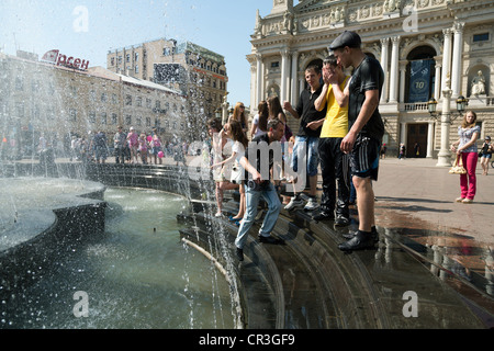 Jugendliche, Chillen am Brunnen vor dem Opernhaus, Lemberg, Ukraine Stockfoto