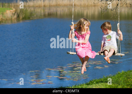 Ein Junge und ein Mädchen sitzen zusammen auf einer großen Schaukel Stockfoto