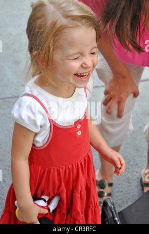 Eine Mädchen lacht genießt sich außerhalb, während Mama in der Nähe ist Stockfoto