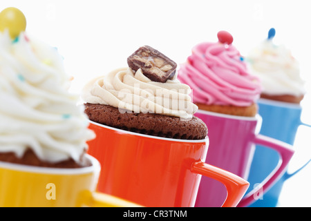 Verschiedene Muffins in bunten Kaffeetassen Stockfoto