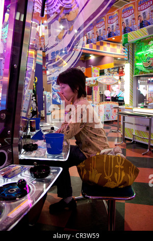 Japanerin mit einem Pachinko-Maschine in eine Spielhalle in Osaka, Japan Stockfoto