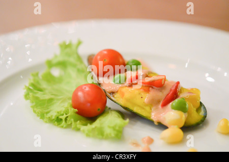 Muscheln unter Käse serviert mit frischem Gemüse Stockfoto