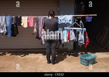 Eine junge Frau hängt die Wäsche auf der Linie. Stockfoto