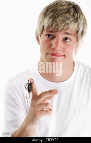 Junger Mann mit nachdenklichen Ausdruck hält einen Schlüsselring auf seinen Zeigefinger Stockfoto