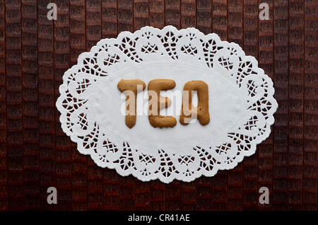 Tee, geschrieben mit Alphabet Kekse auf ein Papier Deckchen Stockfoto