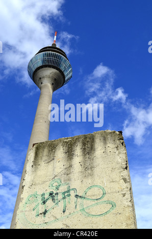 Ein Stück der Berliner Mauer vor dem Turm Rheinturm, Düsseldorf, Nordrhein-Westfalen, Deutschland, Europa Stockfoto