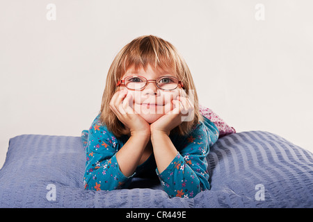 Mädchen mit Brille auf einem Kissen liegend Stockfoto