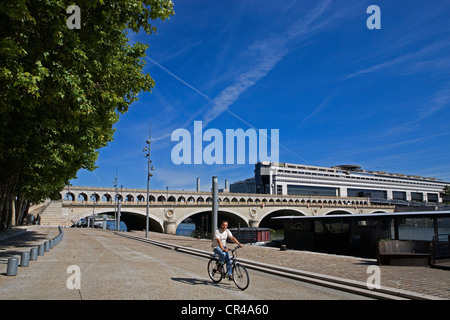 Frankreich, Paris, Radfahren auf dem Quai François Mauriac, Pont de Bercy und Ministerium für Wirtschaft und Finanzen im Hintergrund Stockfoto