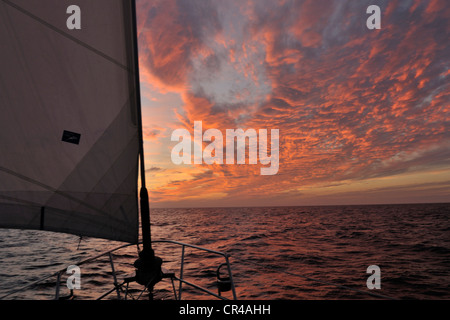 Eine Fahrtenyacht segelt Süd-west durch das Karibische Meer bei Sonnenuntergang. Stockfoto