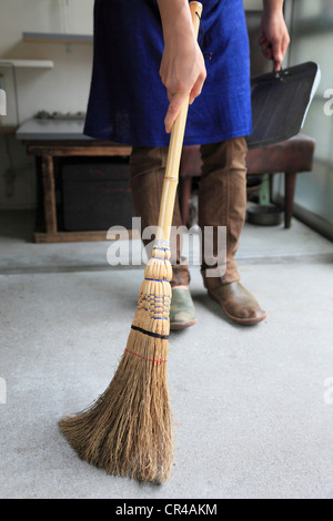 Junge Frau fegen Zimmer mit Besen Stockfoto