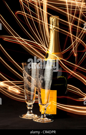 Rot und gold Lichtspuren wirbeln um eine Flasche Champagner und zwei Gläser Champagnerglas Stockfoto