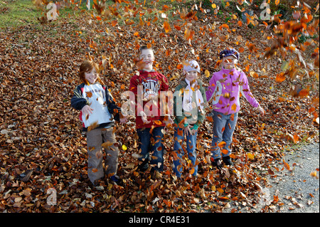 Kinder spielen und werfen mit Blättern im Herbst Stockfoto