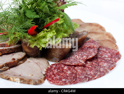 Fleisch auf einem weißen Teller sortiert: Salami, Wurst, Zunge Stockfoto