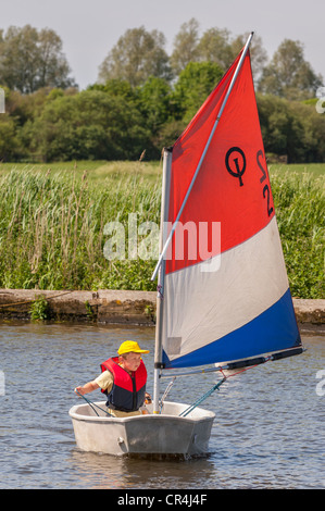 Ein acht Jahre alter Junge Segeln in ein Optimist-Jolle im Vereinigten Königreich Stockfoto