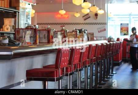 Ein Schuss von einem leeren Frühstück bar in einem Diner mit einer Reihe von leeren Bar Hocker und ein unscharf Kellnerin an der Kante des Rahmens Stockfoto