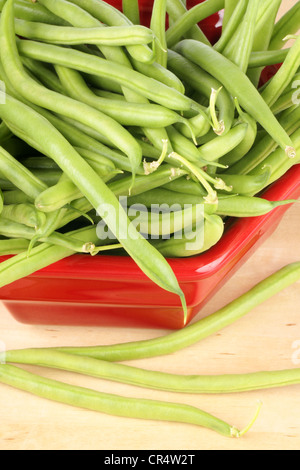 Frische grüne Bohnen in einer roten Schüssel über einem hölzernen Hintergrund Stockfoto