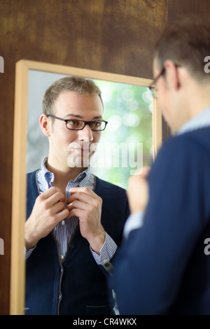 Porträt des jungen Mann mit Brille, immer bereit, verkleiden und mit Blick auf Spiegel Stockfoto