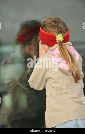 Mädchen, 6 Jahre, Blick durch ein verspiegeltes Glas-Oberfläche Stockfoto