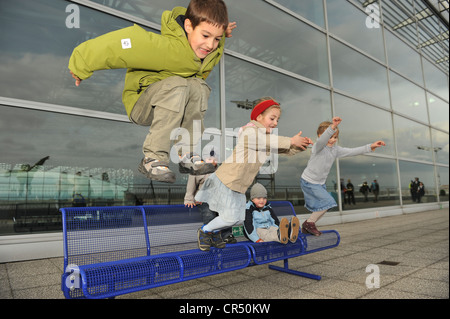 Kinder zwischen 3 und 7 Jahren, springen zusammen von einer Bank am Flughafen, Flughafen Frankfurt, Frankfurt Am Main, Hessen Stockfoto